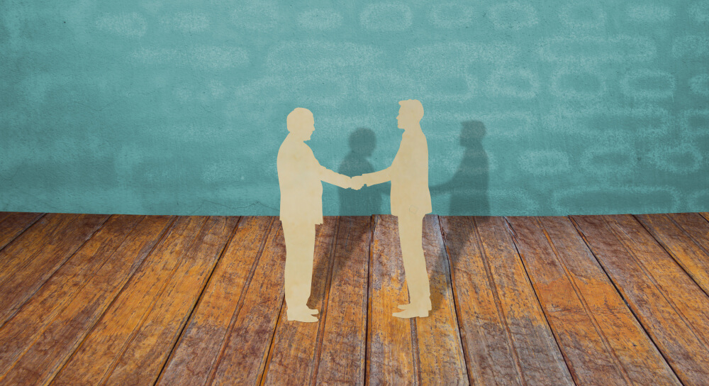 two paper cutouts of business people shaking hands